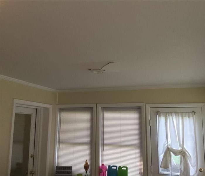 A small sun room has a crack in the ceiling where water came through and affected the room