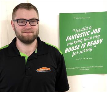A male SERVPRO employee is standing in front of a SERVPRO sign.