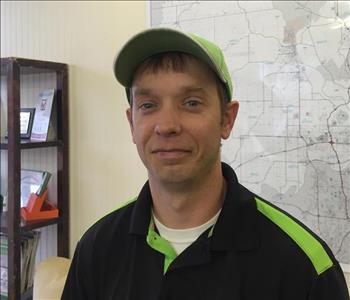 A male SERVPRO employee is standing in front of a sign.