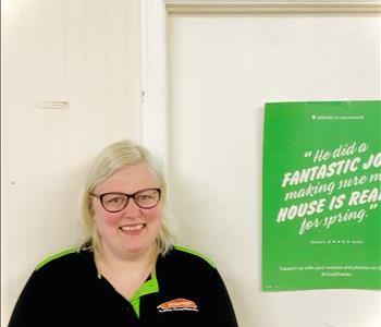 A female SERVPRO employee is standing in front of a SERVPRO sign.